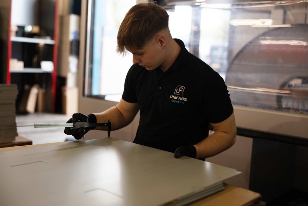 Apprentice checking measurements to ensure part is within tolerance