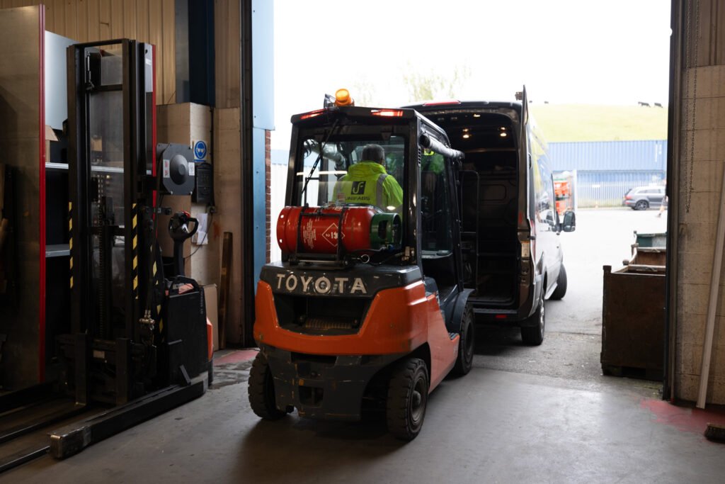 forklift driver loading manufactured sheet metal products into the back of a delivery van