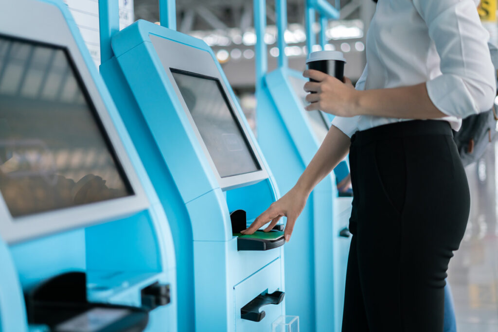 Stock image of a woman at a digital self service kiosk displaying Self-Service Kiosk Manufacturing abilities in the UK