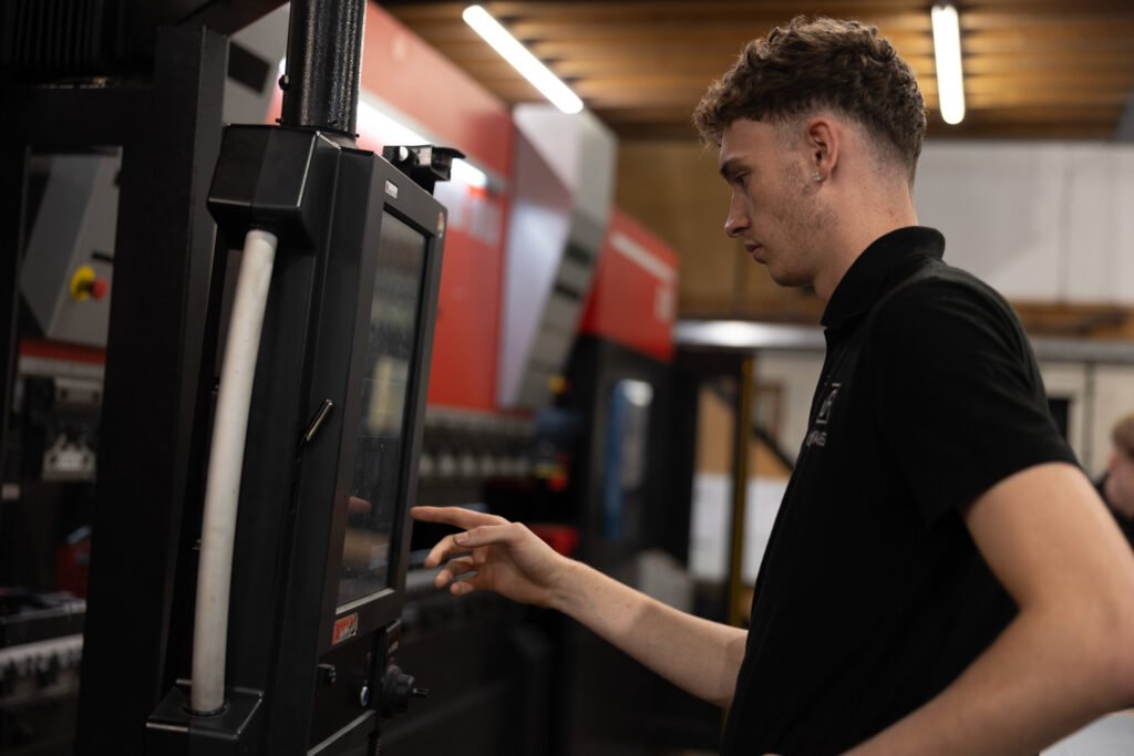 worker at press brake using the HMI setting up machine with automatic tool change ready for the next product