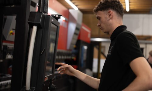 worker at press brake using the HMI setting up machine with automatic tool change ready for the next product for press braking