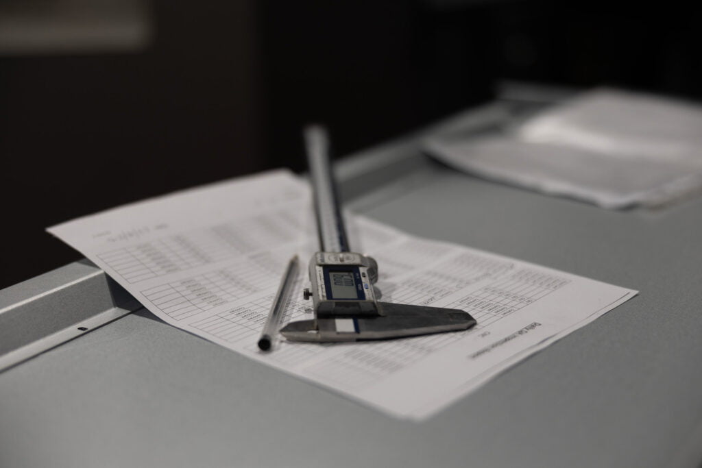 digital vernier caliper laying on paperwork for measuring sheet metal manufactured products