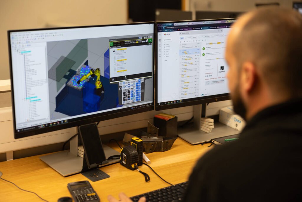 Design engineer running program for robotic welding on computer