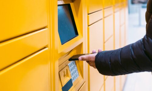 stock image of a Person using Click and collect lockers with a mobile phone in their hand showcasing the kind of lockers Unifabs is able to manufacture