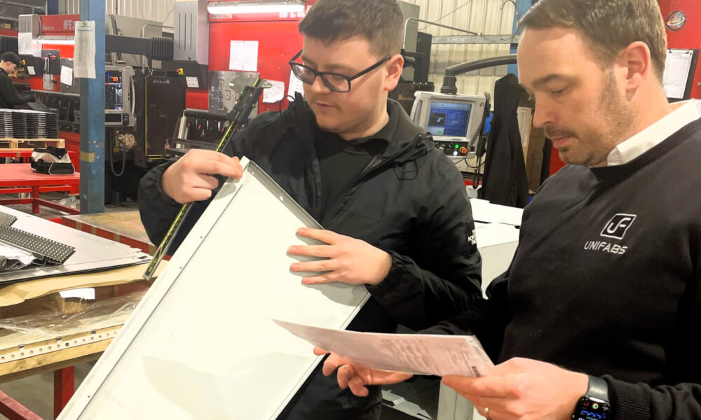 Engineering Manufacturing Technician Apprentice Owen and supervisor Dan inspect quality of a manufactured part