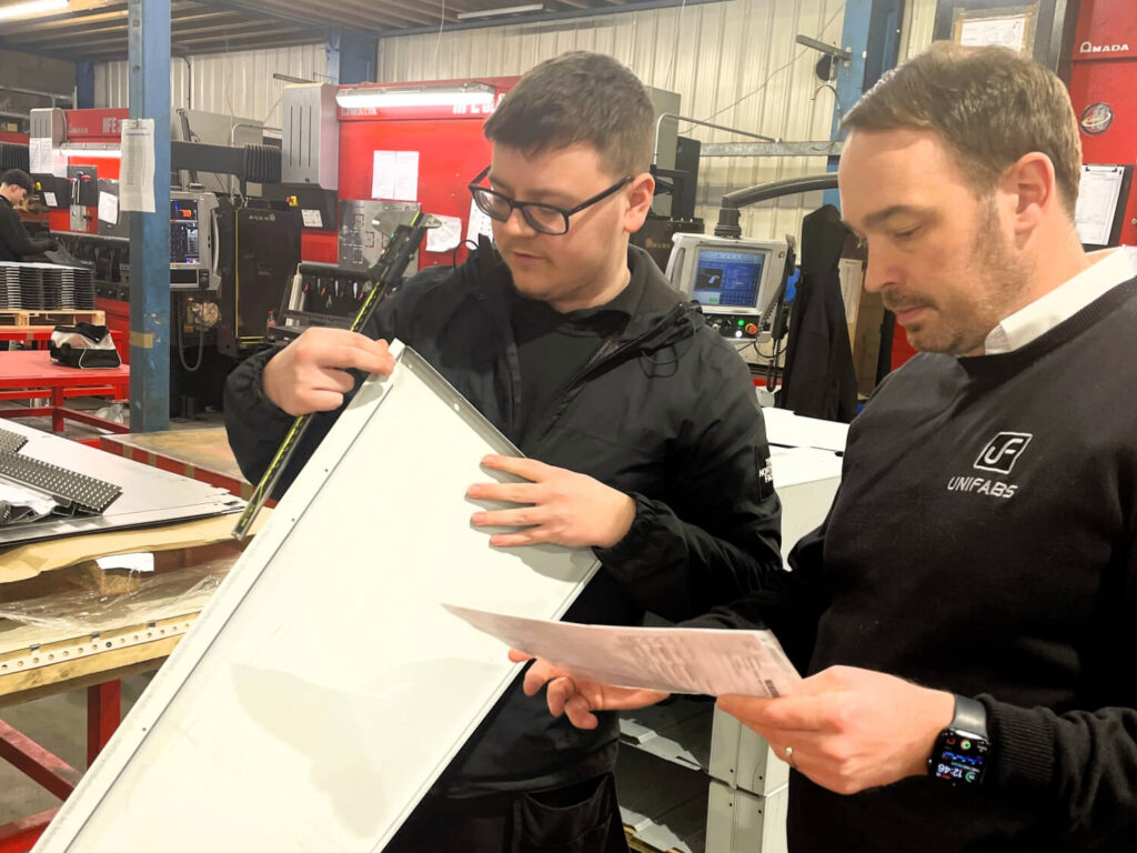 Engineering Manufacturing Technician Apprentice Owen and supervisor Dan inspect quality of a manufactured part