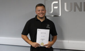 Newly qualified as a CAD Engineer, Jamie Hamilton stands with his Apprenticeship certificate