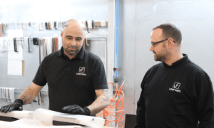 Chris Lawrence Production Manager discusses product packing with sheet metal fabrication team operator at the Unifabs site based in Nuneaton UK. Powder coating line is visible in the background with various coloured hanging hooks.