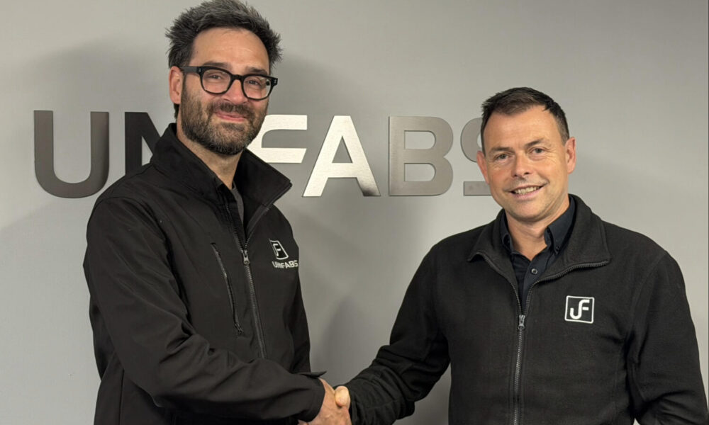 Gary Moreton achieves 10 years' service milestone at UK sheet Metal Fabricator Unifabs Ltd. Pictured with Andy Tuck shaking hands in front of a Unifabs sign on a grey wall.