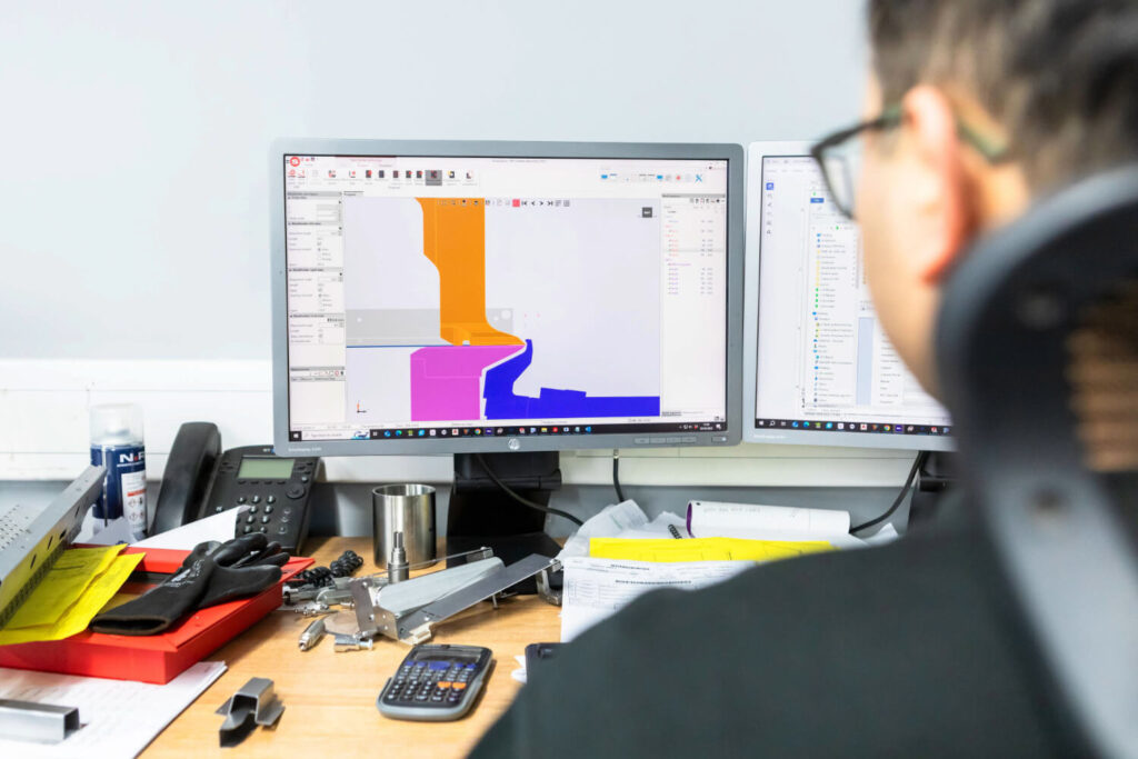 Designer sat at desk, with CAD design on screen utilising Salvagnini panel bending at Unifabs Ltd