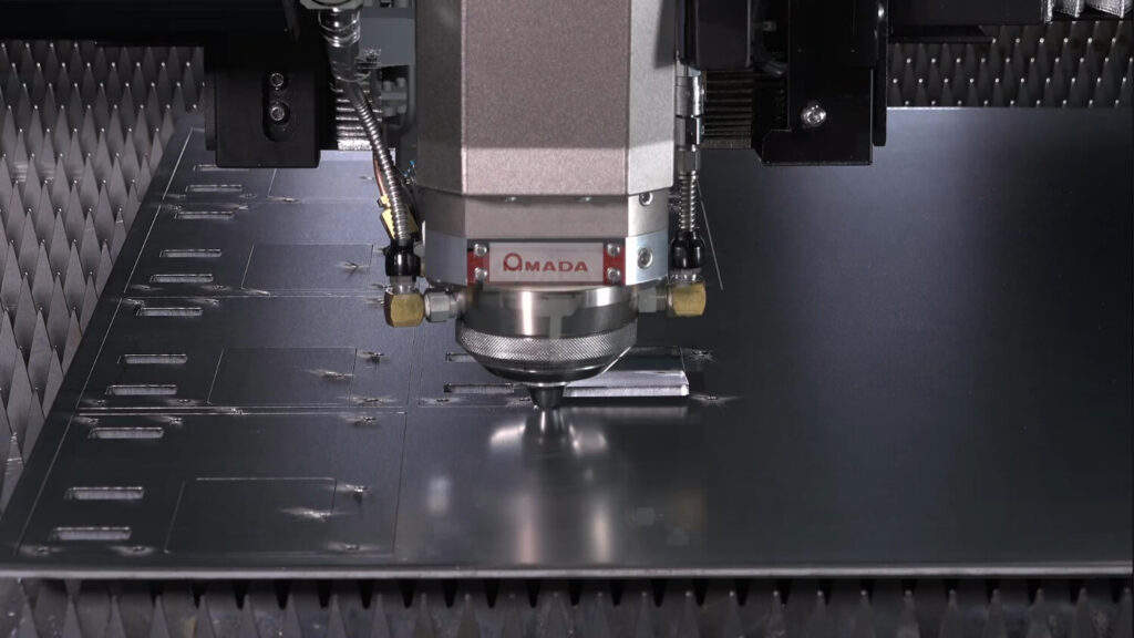 AMADA REGIUS-AJ fibre laser cutting head clos up inside machine cutting sheet metal